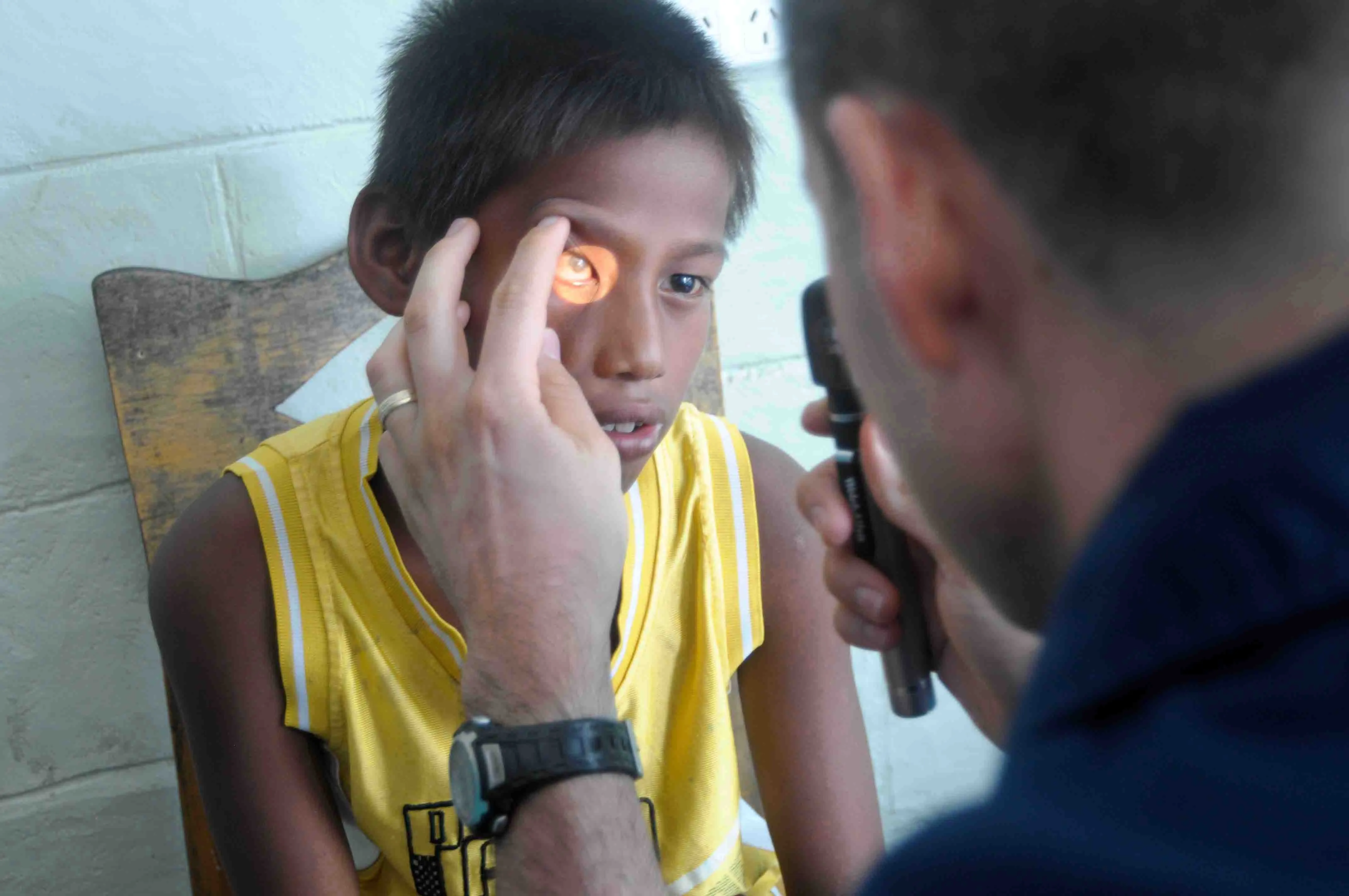 An optometrist examines a young child's eyes during a community healthcare outreach eye examination