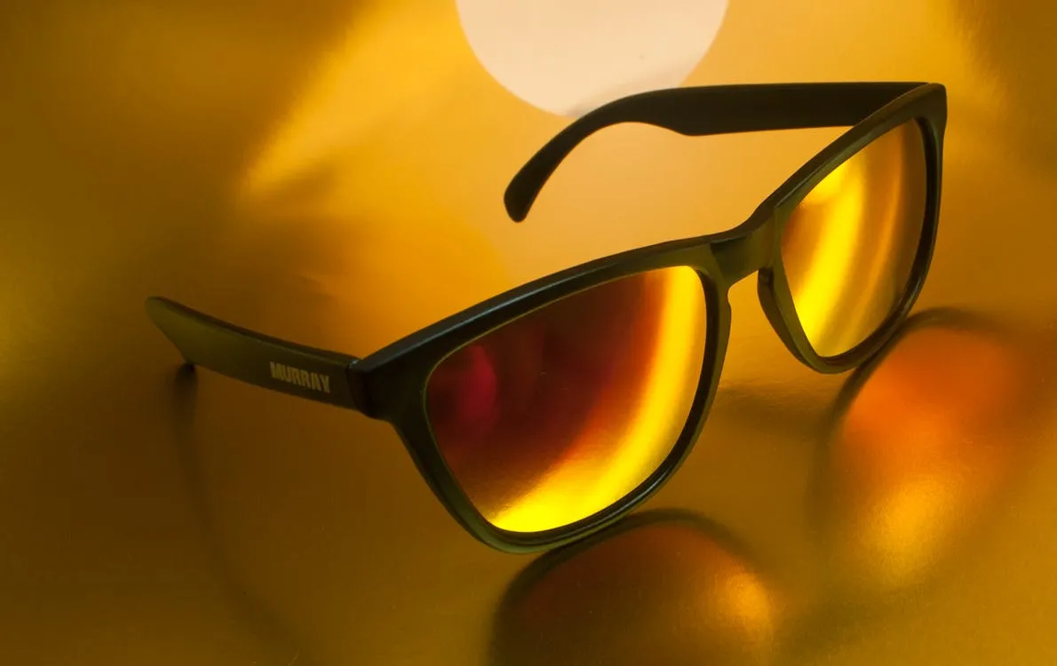 Close-up of luxury fashion sunglasses with reflective lenses on a vibrant background